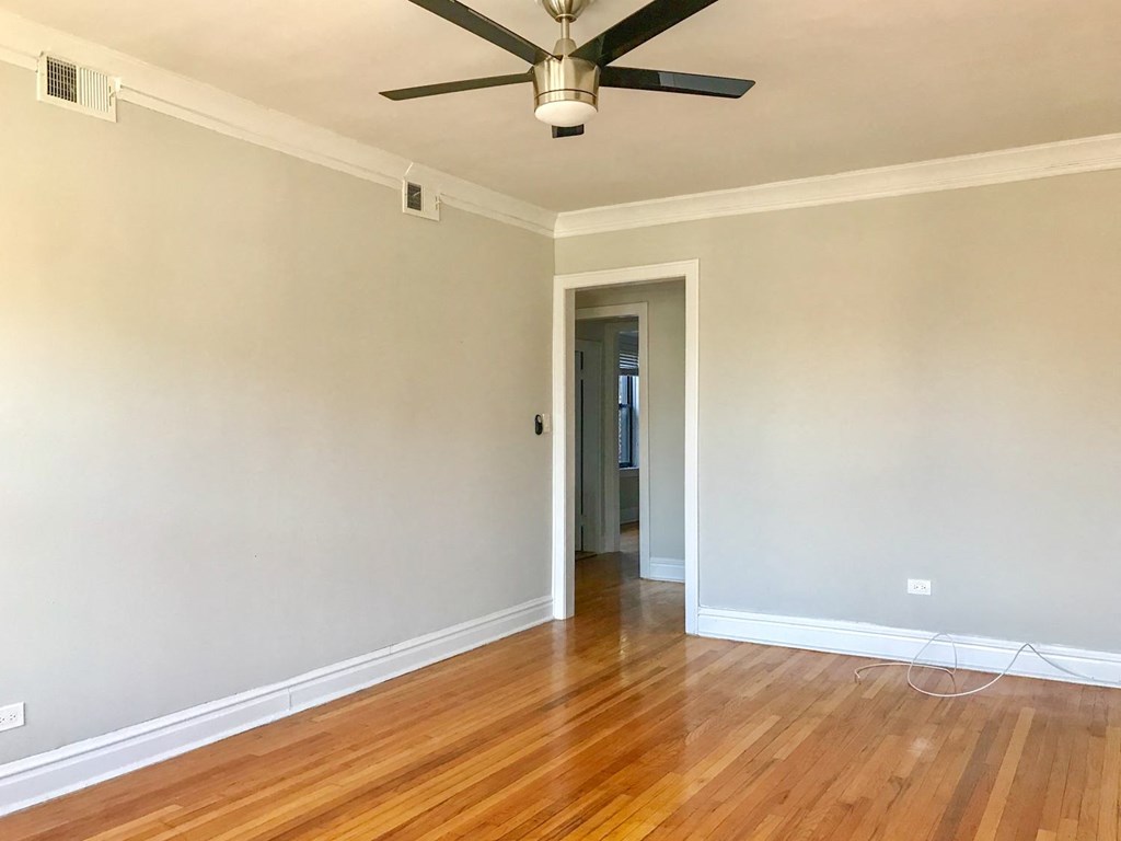 an empty living room with wood floors and a ceiling fan