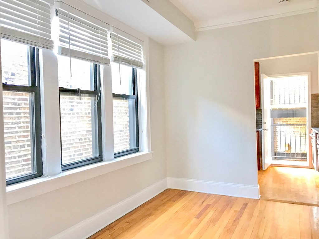 a living room with three windows and a hard wood floor