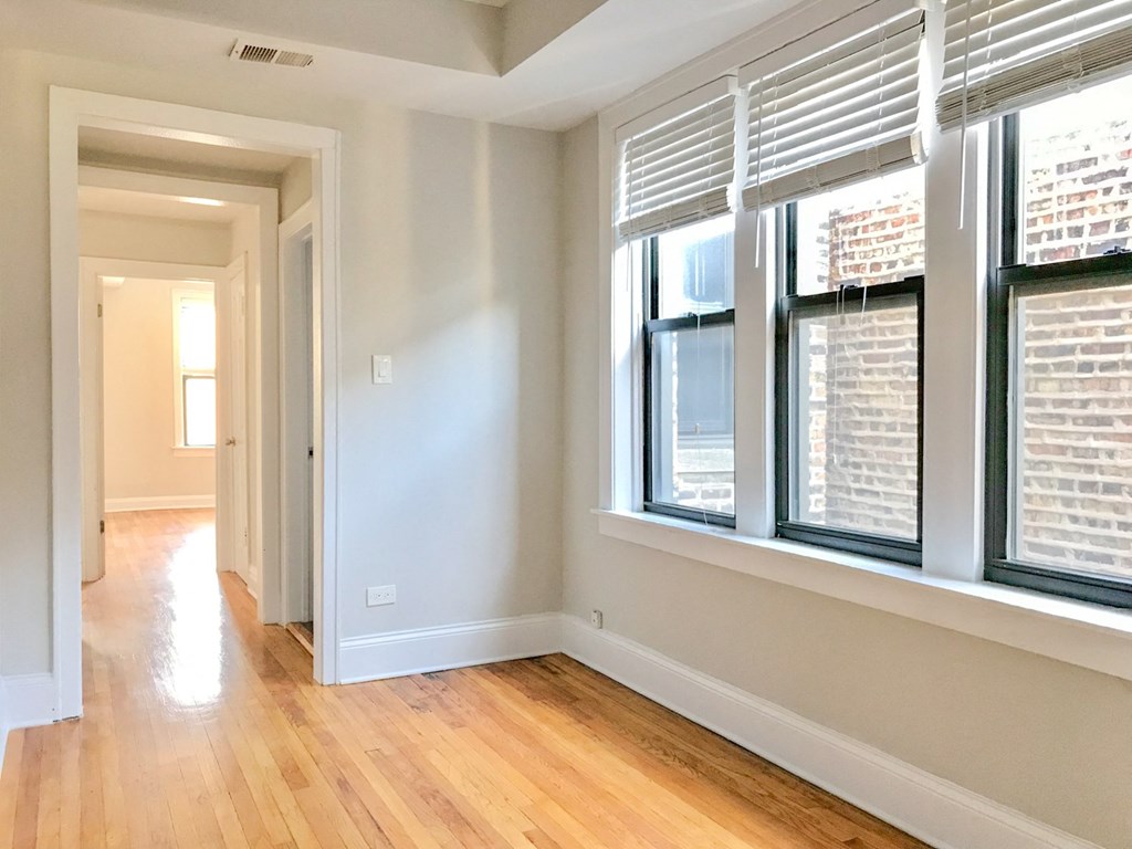 an empty living room with three windows and a wood floor