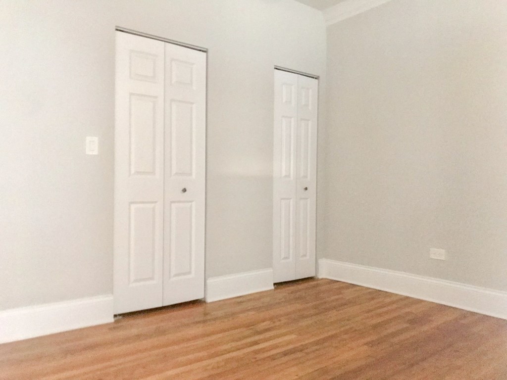 an empty room with two doors and a wood floor