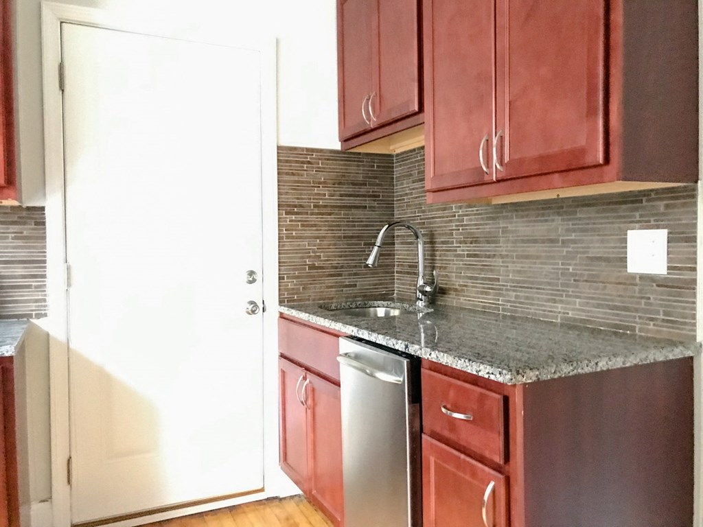 a kitchen with red cabinets and a sink and a refrigerator