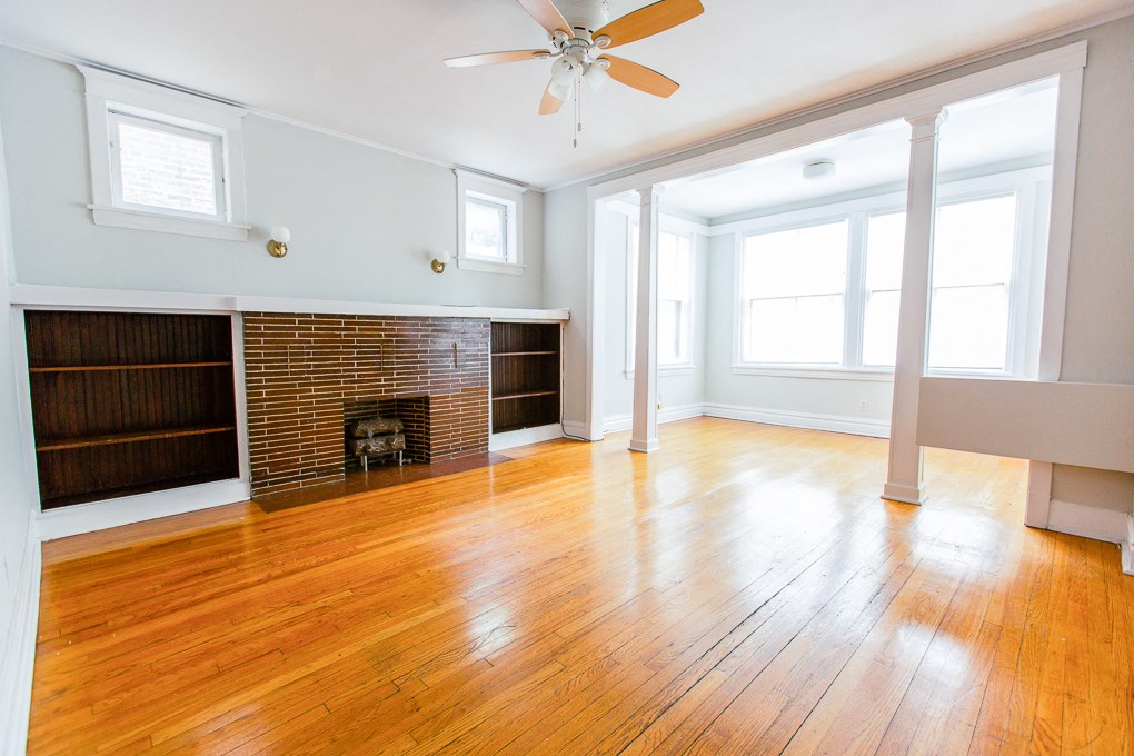 an empty living room with wood floors and a brick fireplace