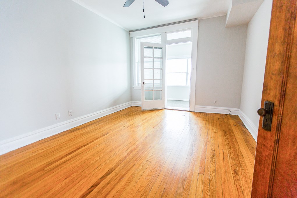 an empty living room with wood floors and a door to a balcony