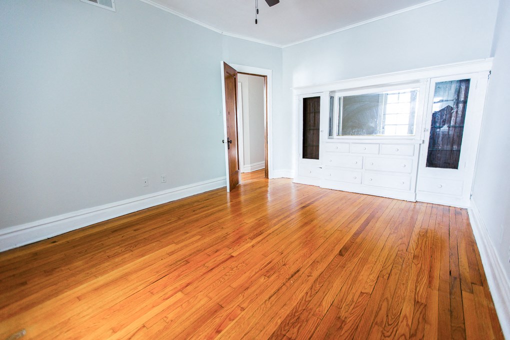 an empty living room with wood floors and a door to a bedroom