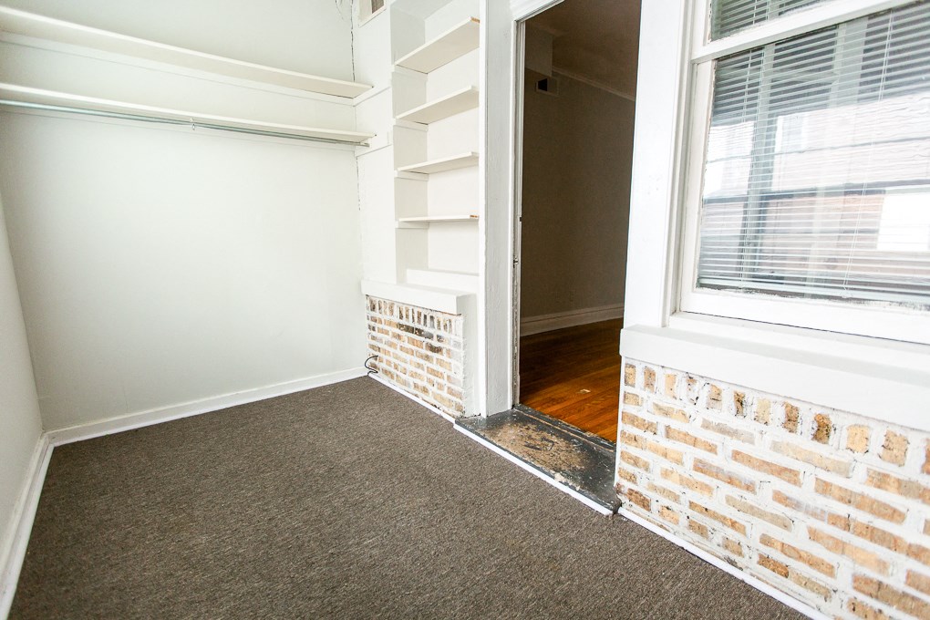 a doorway into a room with a brick wall and a window
