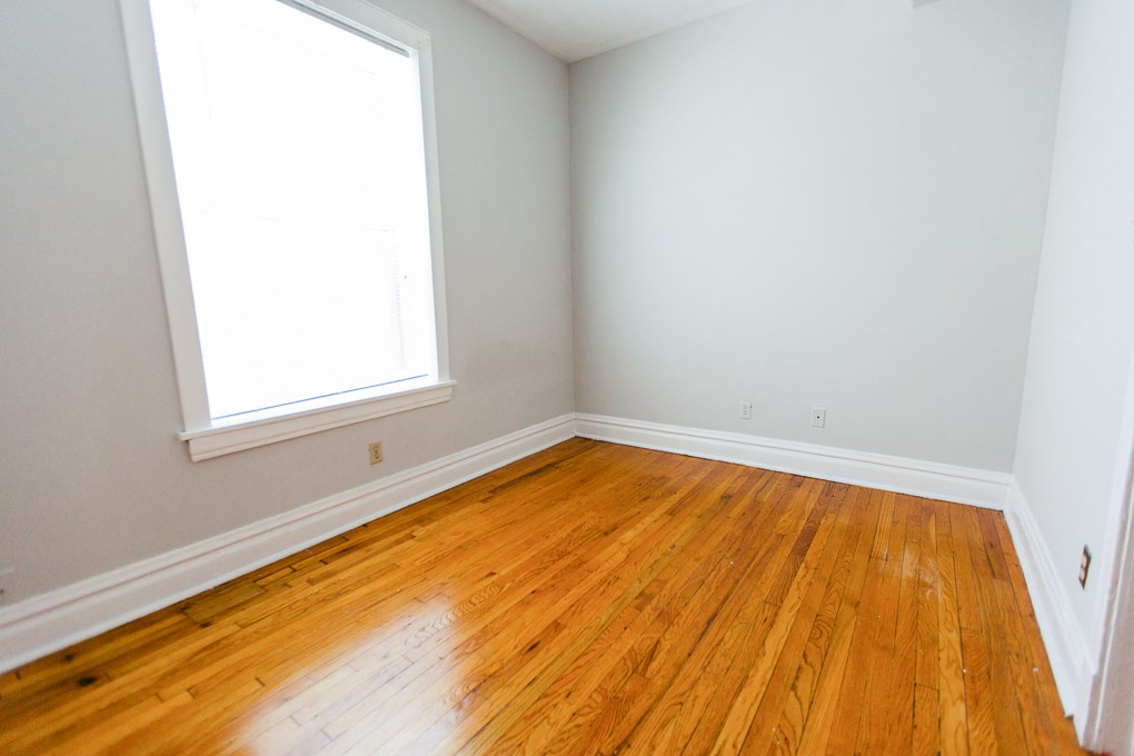 an empty room with wooden floors and two windows