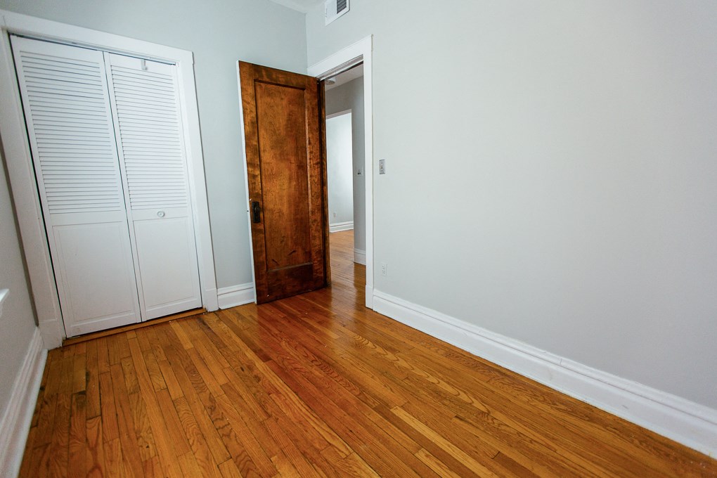 a bedroom with wood flooring and a door to a closet