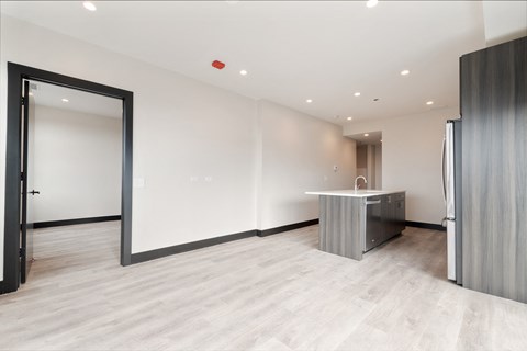 a large room with a kitchen and a door to a hallway