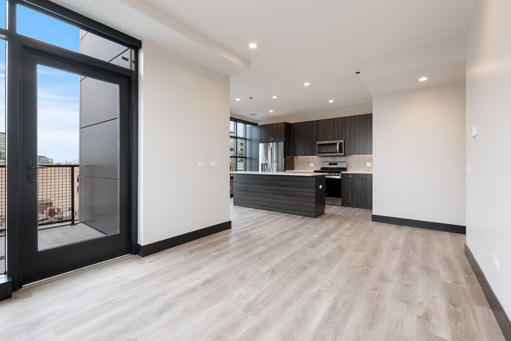a living room with a kitchen and a large glass door