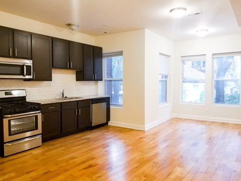A kitchen with black cabinets and wooden floors.