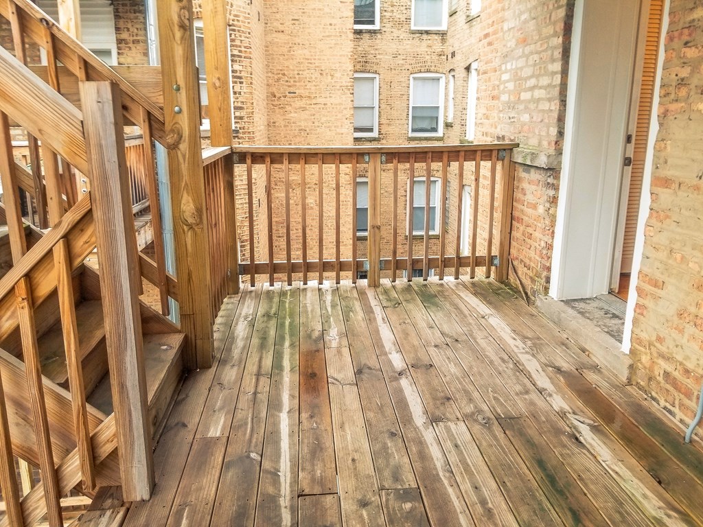 a balcony with wooden floors and a brick building in the background