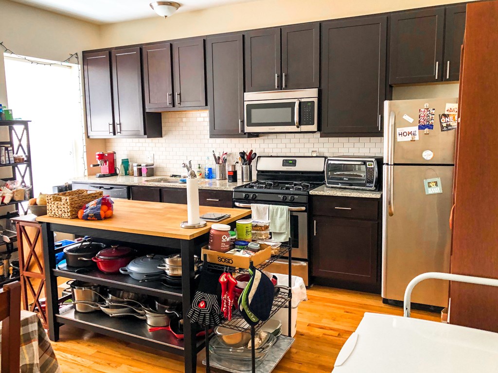 A kitchen with a refrigerator, oven, and microwave.