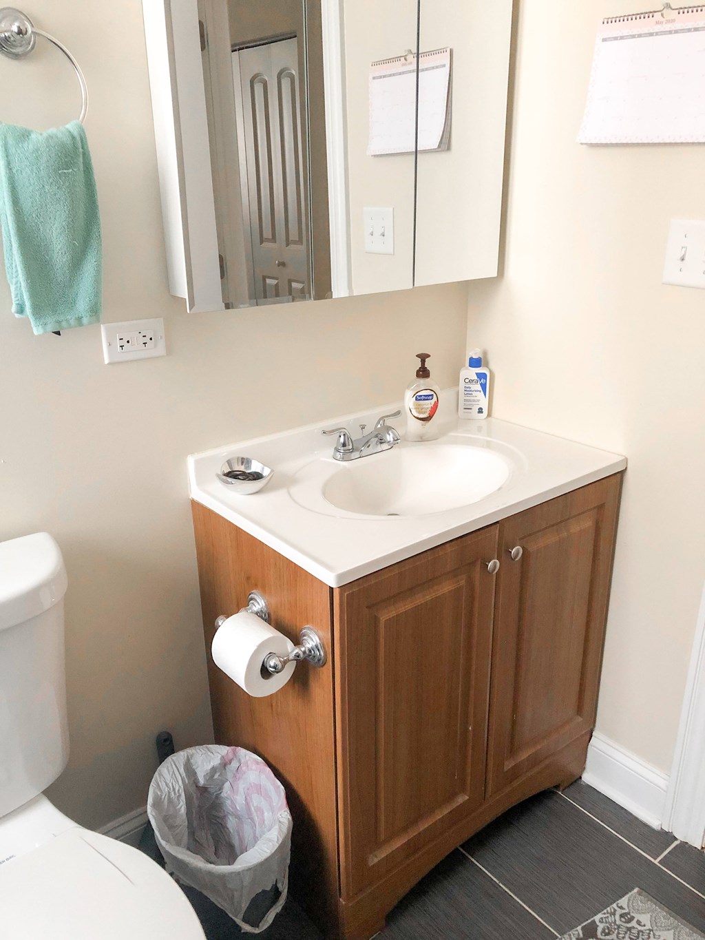 A bathroom with a toilet, sink, and mirror.