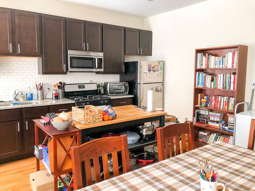 A kitchen with a table and chairs and a bookshelf.