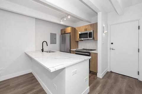 A kitchen with a white countertop and wooden cabinets.