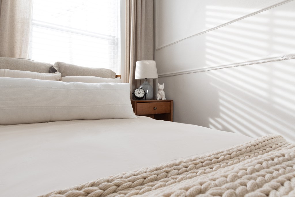 a bed with a white blanket and a clock on a night stand