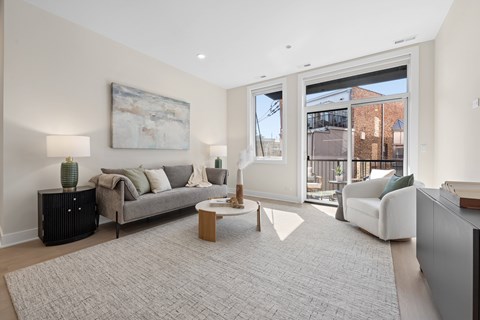 A living room with a grey sofa, a grey rug, a wooden coffee table, and a painting on the wall.