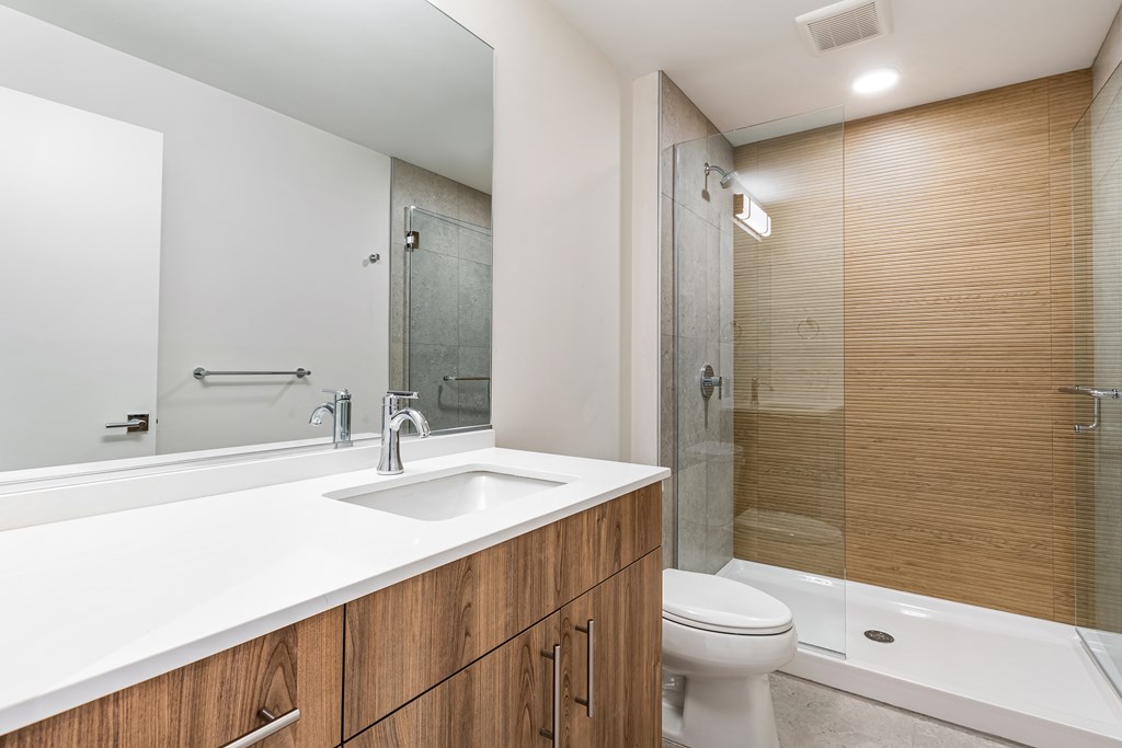 A modern bathroom with a white sink and wooden cabinets.