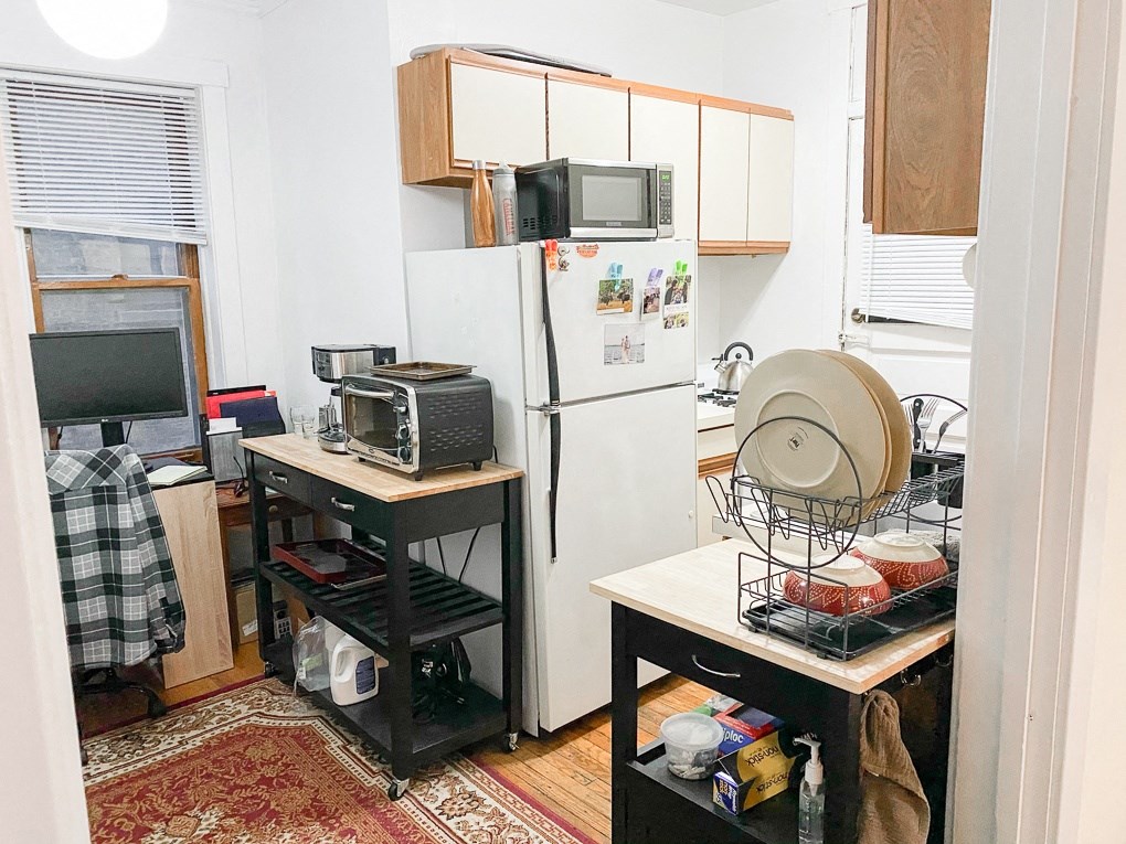 a small kitchen with a refrigerator and microwave and a table