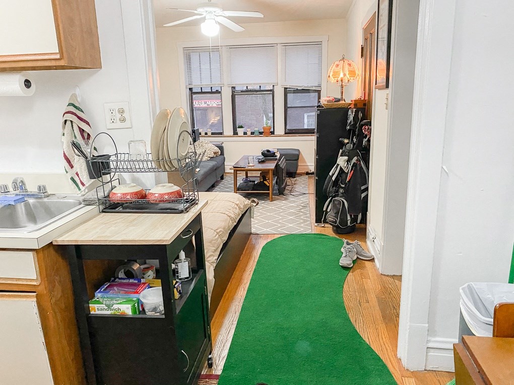 a small kitchen with a green rug in front of a living room