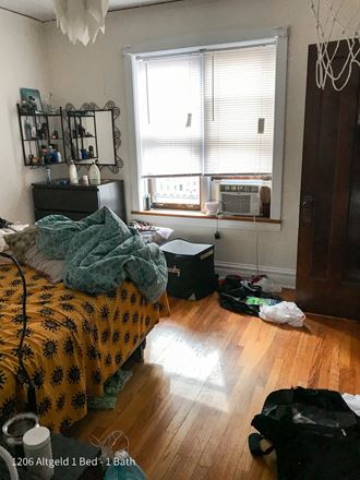 a bedroom with a bed and an air conditioner in the window
