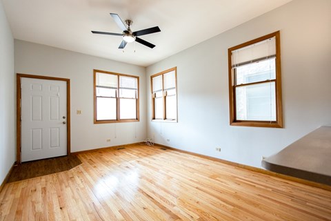A room with a ceiling fan and three windows.