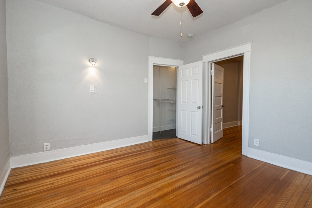 an empty living room with wood flooring and a ceiling fan