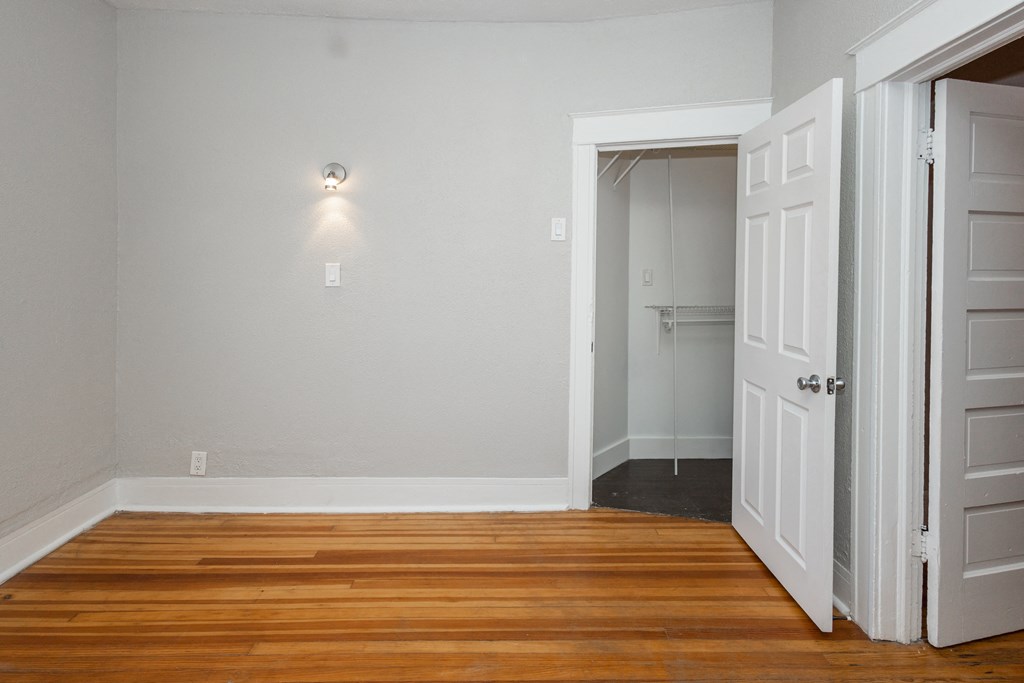 a bedroom with wood floors and white doors and a closet