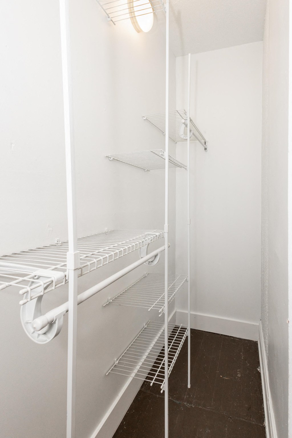 a walk in closet in a small room with white walls and shelves and a glass