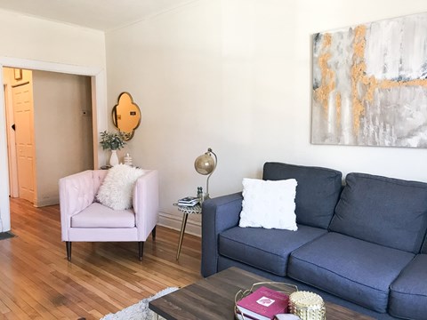 A living room with a pink chair and a blue couch.