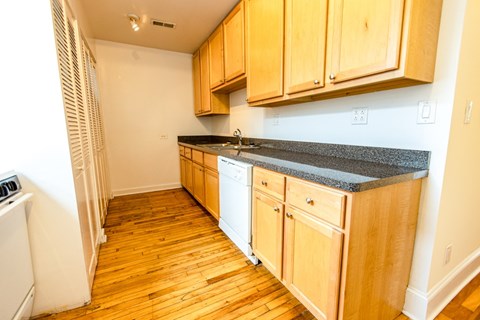 A kitchen with wooden cabinets and a white dishwasher.