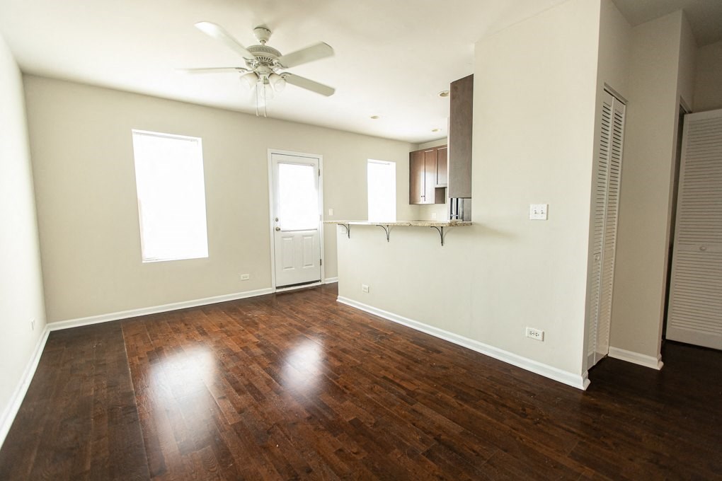 an empty living room with wood floors and a ceiling fan