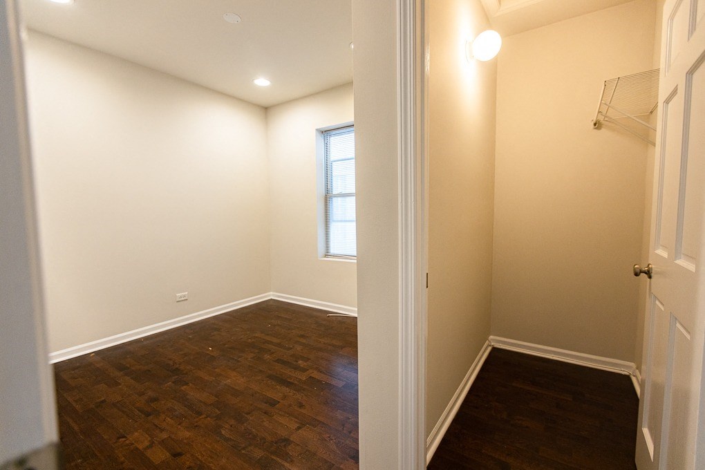 a bedroom with a wood floor and white walls and a window