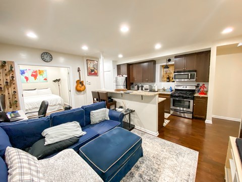 A living room with a blue couch and a guitar on the wall.
