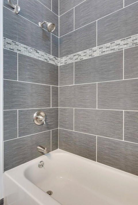 A white bathtub with a silver faucet and a silver shower head.