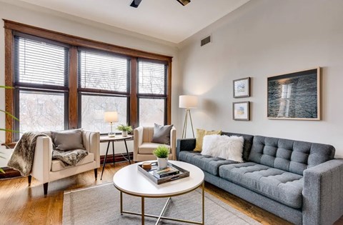 A living room with a grey couch, a white coffee table, and a large window.