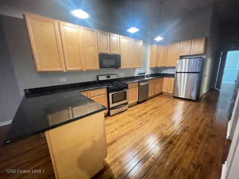 A kitchen with wooden cabinets and black countertops.