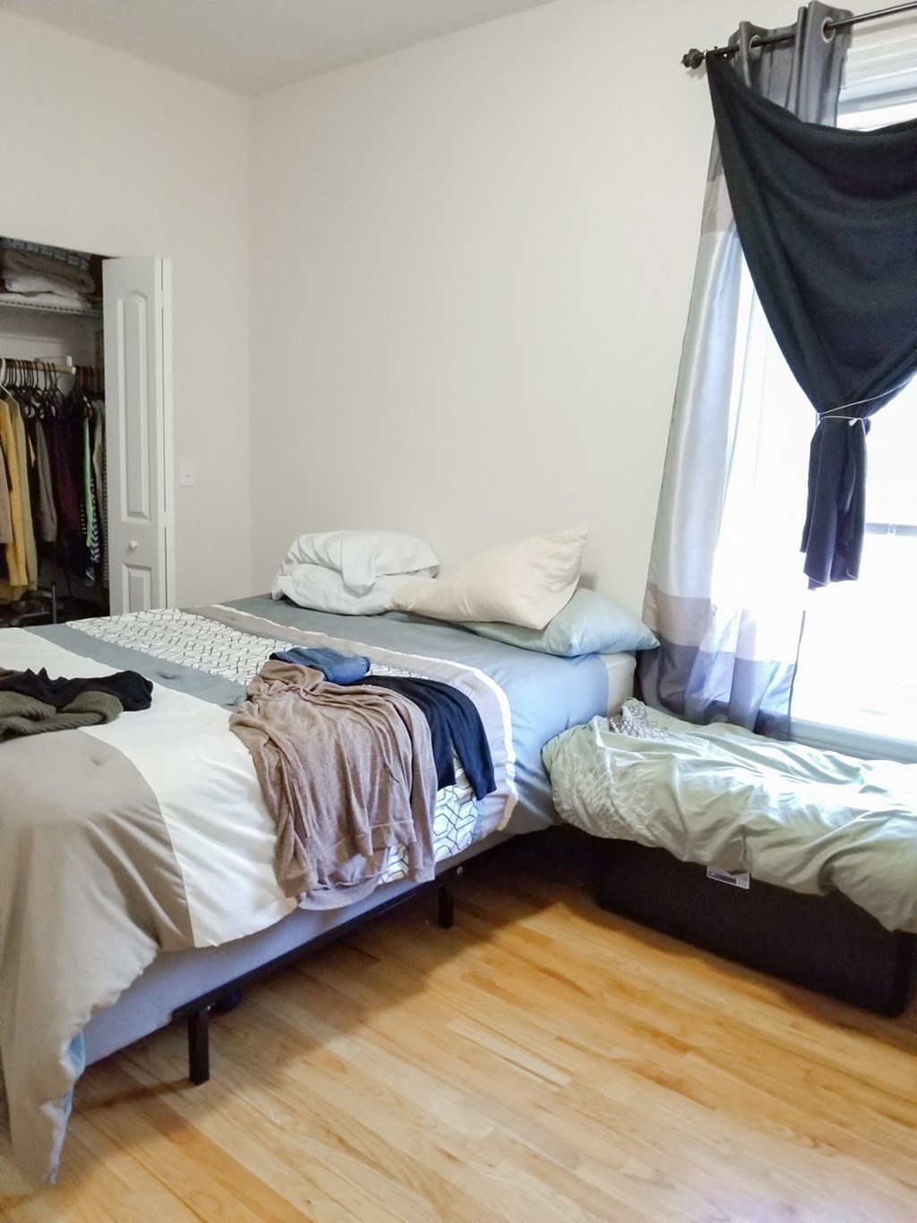 a bedroom with two beds and a closet with clothes on them