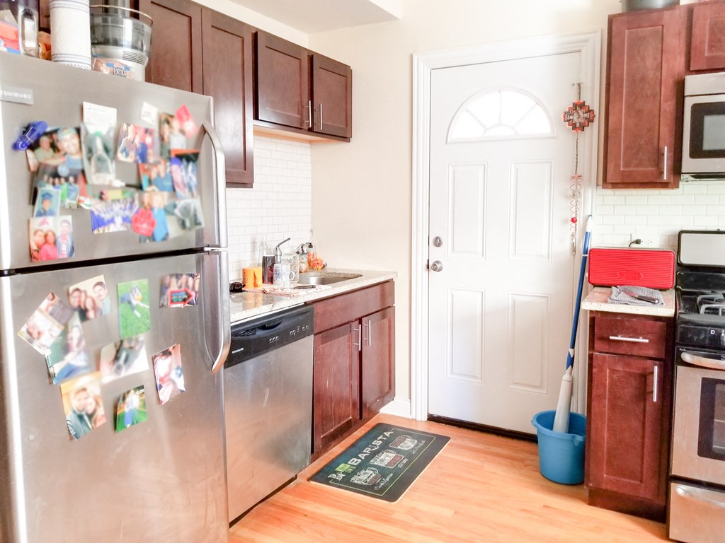 a kitchen with stainless steel appliances and a refrigerator covered in magnets