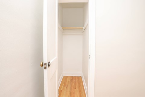 a room with white walls and wood floors and a closet