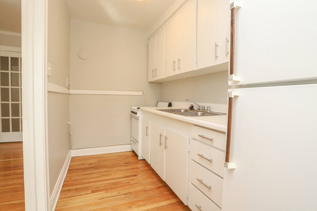 a kitchen with white cabinets and a sink and a refrigerator