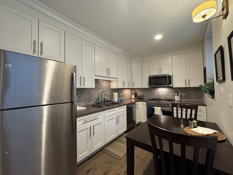 A kitchen with a stainless steel refrigerator and wooden table.
