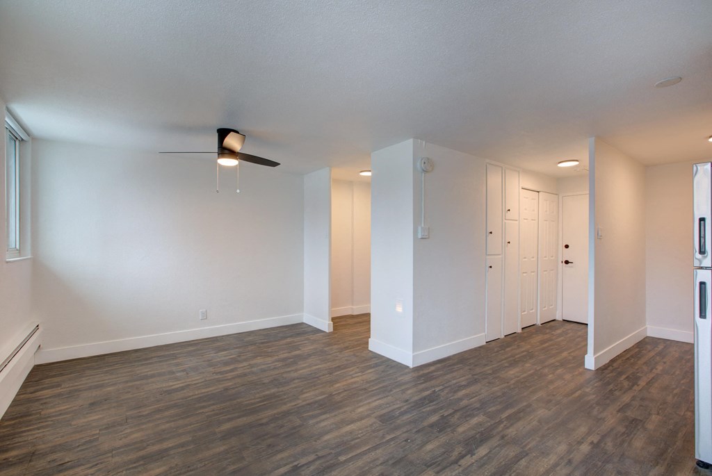 an empty living room with wood flooring and a ceiling fan