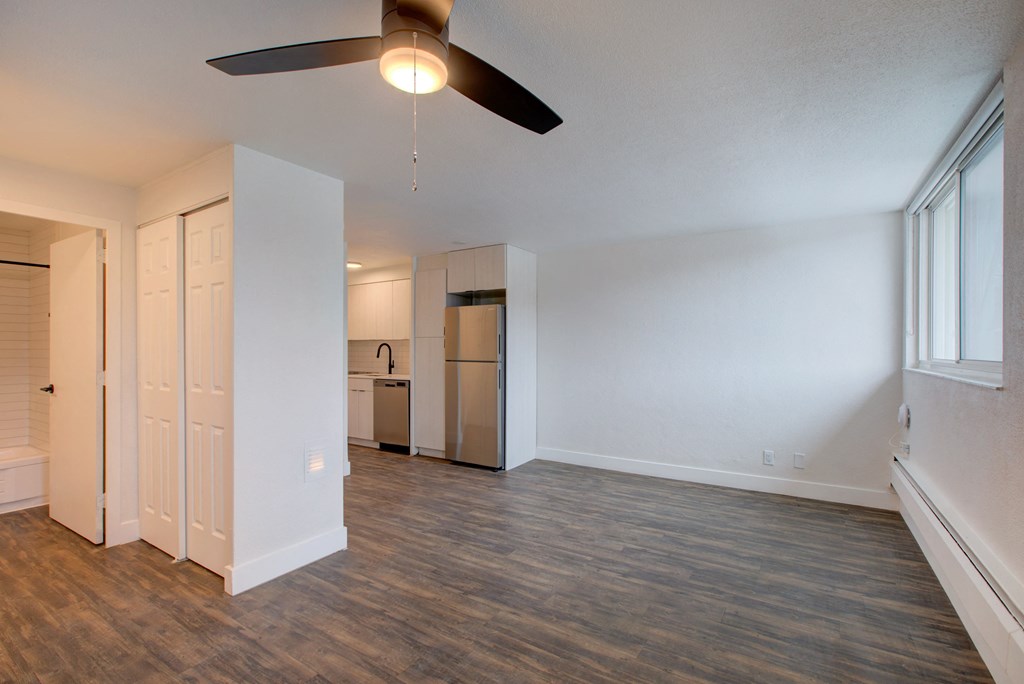 an empty living room with a ceiling fan and a kitchen