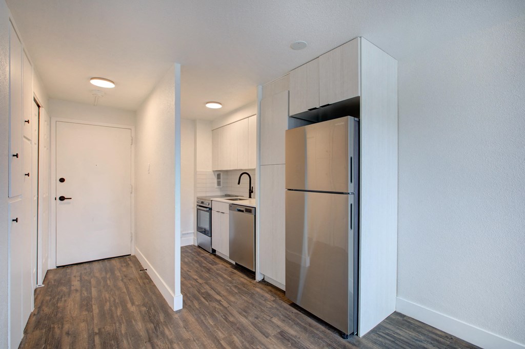 an empty apartment with a kitchen and a refrigerator