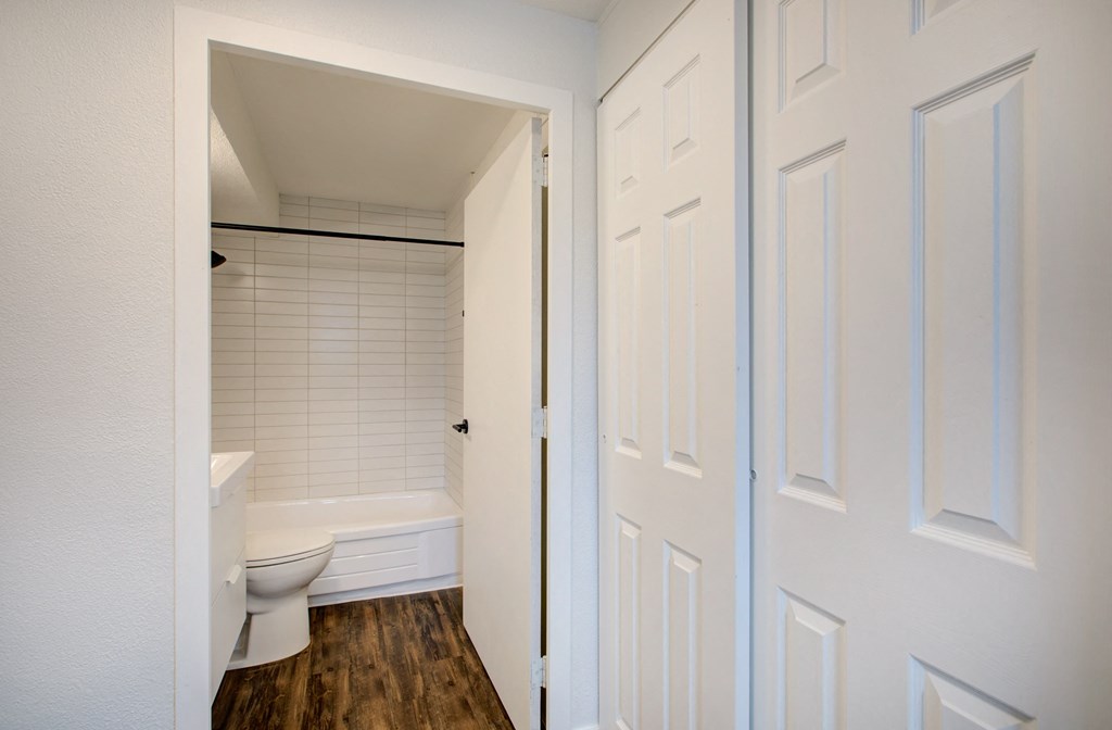 a bathroom with a white toilet and a tub and a closet