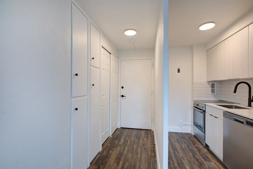a kitchen with white cabinets and white appliances and a wood floor