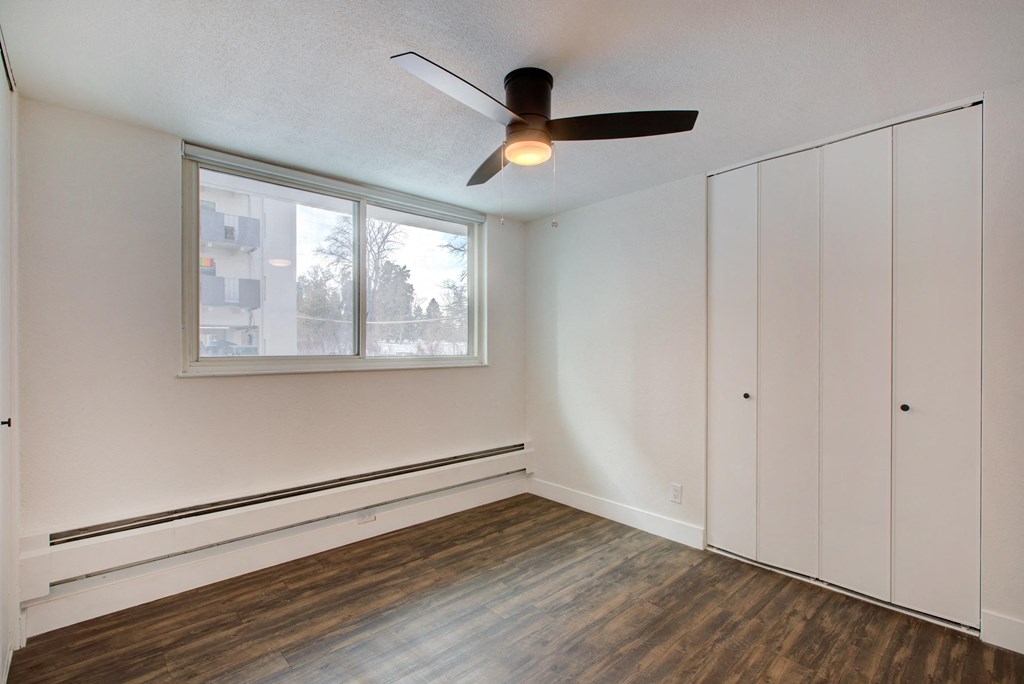 a bedroom with white walls and a ceiling fan and a window