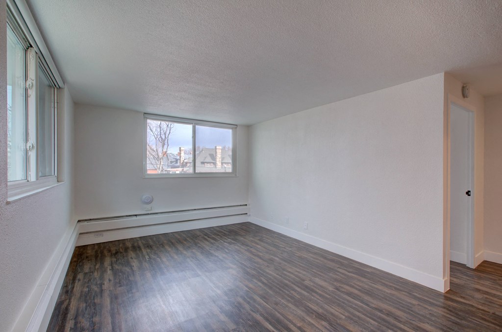an empty living room with wood flooring and a window