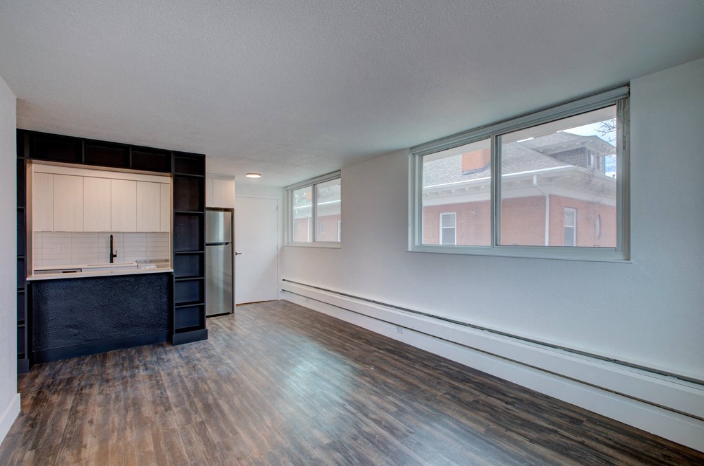 an empty living room with a window and a kitchen